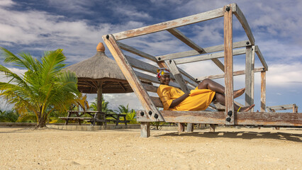 Obraz na płótnie Canvas African woman enjoying leisure on a wooden sunbed located on a beach in the village of Keta Ghana West Africa