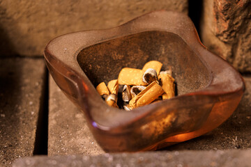 Cigarette butts in a glass ashtray.