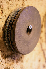 Cutting and grinding wheels suspended from a screw in the wall.