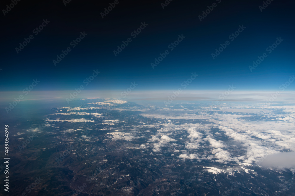 Wall mural view from the airplane window to mountains clouds and blue sky