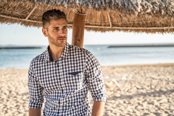 Handsome young italian man posing on the beach,, wearing fashionable shirt, summer time