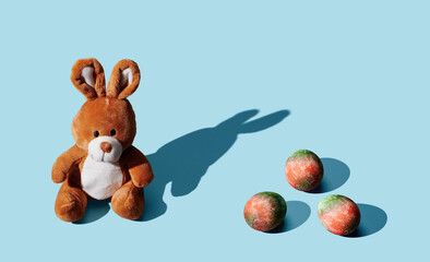 soft toy bunny with easter egg on blue pastel background