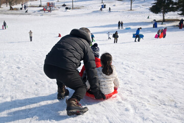 Winter sport toboggan -  father and daughter playing toboggan, winter, outside, healthy lifestyle.