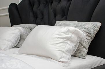 White luxurious satin pillowcases. Close-up detail of a double bed with pillows and linens.