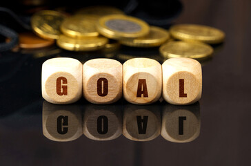 On a black surface are coins and cubes with the inscription - GOAL