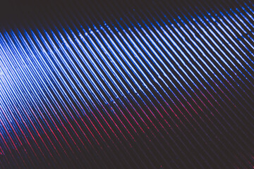 Ridged texture. Blur glow overlay. UV led light reflection. Neon blue red white color radiance on dark black grooved surface abstract background.