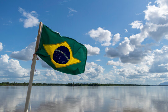 Brazil flag fluttering in the wind with river landscape in the background