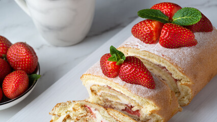 Sweet roll stuffed with strawberry and cream decorated with strawberries, powdered sugar and mint leaves