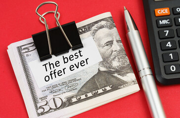 On a red surface lies a calculator, a pen, dollars and paper with the inscription - The Best Offer...