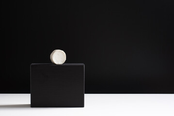 Queso cremoso de cabra sobre soporte negro y fondo negro. Concepto minimalista	