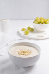 Crema de almendras, sopa fría española. Ajo blanco de Málaga con almendras y uvas en un recipiente blanco sobre una mesa blanca	