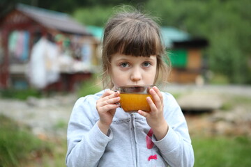 Little girl drinking sea buckthorn tea in a cafe