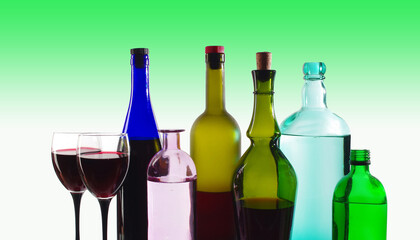 Two glasses with red wine, bottles of wines and spirits on a colored background. 