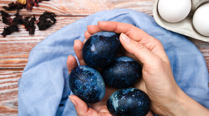 Woman's hands hold painted Easter eggs. The process of dyeing eggs with natural food coloring. Preparation for Easter. Close-up.