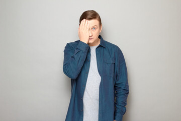 Portrait of blond mature man covering half of his face with hand