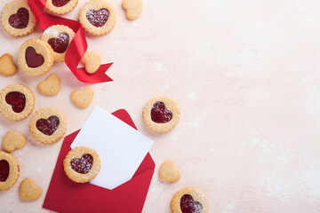 Traditional Linzer cookie with strawberry jam and powder sugar, gift and red ribbon on pink beautiful background. Top view. Traditional homemade Austrian sweet dessert food on Valentines Day.