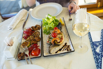 baked trout with grilled vegetables and shrimp and fresh lettuce on a white plate, food and delicacies