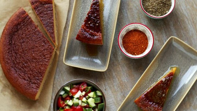 Traditional chickpea flour dish bread with fresh vegetable salad and spices. Moroccan cuisine, table spin.