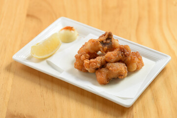 japanese food fried Tako Karaage with lemon in a white dish isolated on wooden table top view