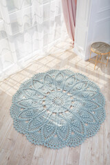 In a bright room on the floor there is a round blue handmade carpet. flooring, natural cotton. Blue...
