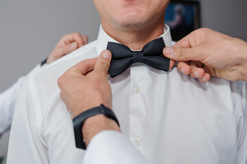 Black bow tie in the hands of the groom. Bow tie in the hands of a man