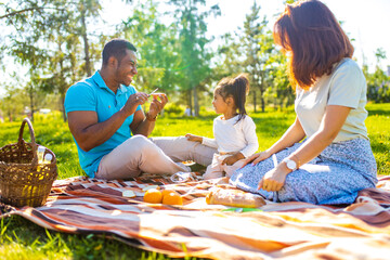 Happy international family enjoying picnic in nature
