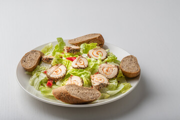 Healthy food. Green lettuce, red pepper, natural cheese and pastries on a white plate. The background is white.