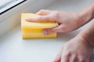 The girl washes the window with a sponge. Home routine. Cleaning 