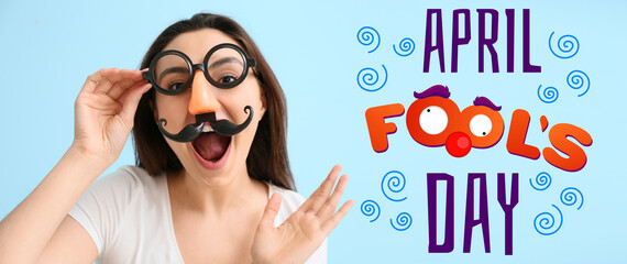 Young woman in funny disguise on blue background. April fools' day celebration