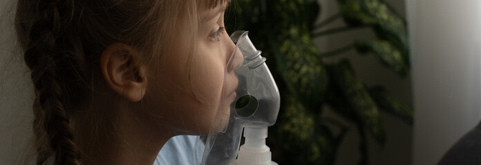 sick little girl makes inhalation over grey background with copy space. Girl making inhalation with...