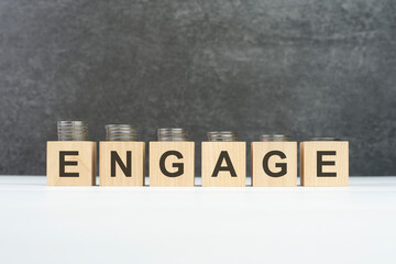 ENGAGE word, text written on wooden cubes on a black background with coins on cubes