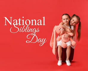 Cute little sisters with toy on red background. National Siblings Day