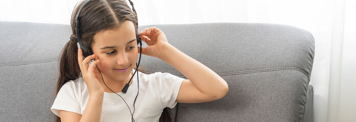 Homeschool little young girl student learning virtual internet online class from school teacher by remote meeting due to covid pandemic. Female teaching math by using headphone.