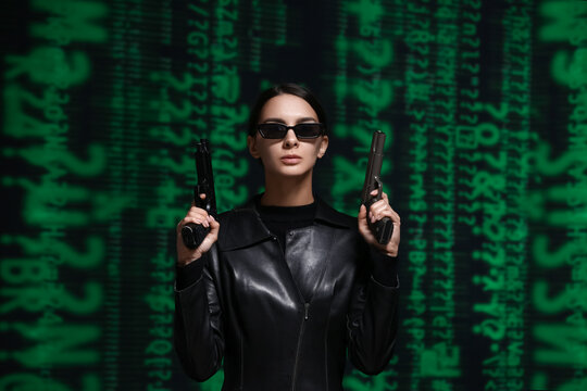 Woman with guns dressed in matrix style on dark background