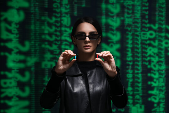 Woman dressed in matrix style with blue and red pills on dark background. Concept of choice