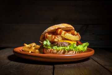 Premium quality burger with onion rings, cheese and barbecue sauce, served with french fries on a...