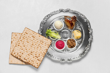 Passover Seder plate with traditional food and matza on white background