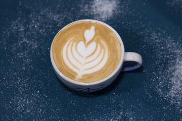 Big cup of coffee on a blue background. Drawing of a tulip on coffee. Cappuccino 
