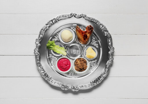 Passover Seder plate with traditional food on white wooden background