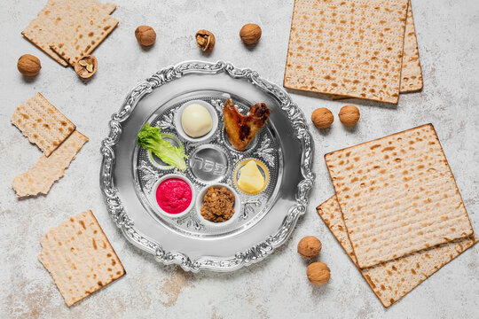 Passover Seder plate with traditional food, walnuts and matza on light background