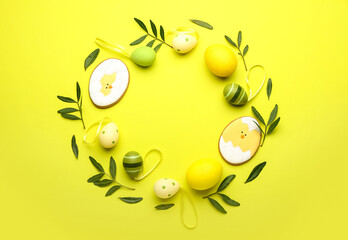 Stylish wreath with Easter eggs, cookies and leaves on yellow background
