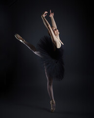 attractive ballerina stands on her fingertips. photo shoot in the studio on a dark background