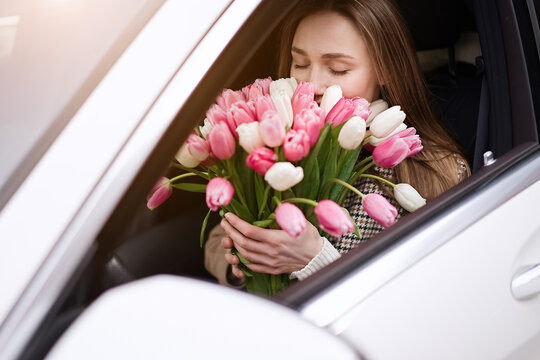 Beautiful girl with tulip flowers in her hands in the car  