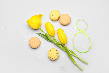 Figure 8 made of ribbon, tulip flowers and sweet macaroons on white background. International Women's Day celebration