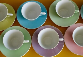 Aerial view of vintage pastel tea cups on yellow table. Afternoon tea party.