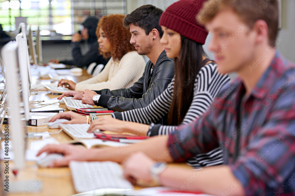 Poster Focussed on their studies. Shot of students working on computers in a university library.