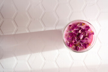 Pink rose milk with rose petals in a glass. Healthy drink moon milk. Top view.