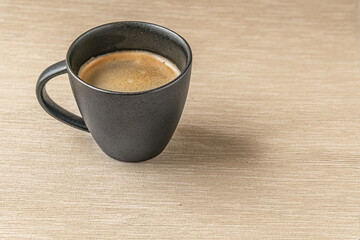 aromatic freshly brewed coffee in a black ceramic cup on a burlap cloth