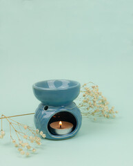 Essential oil in an aroma lamp on a blue background, vertical, copy space