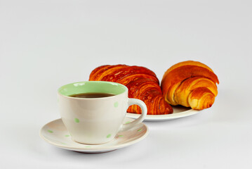 Yellow croissant in a plate and coffee isolated on a white background. Classic breakfast close up.